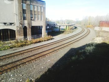 Railroad tracks by buildings in city against sky