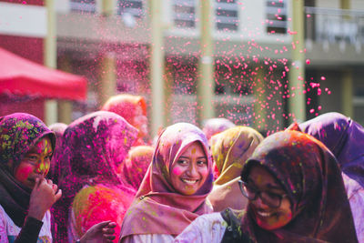 Smiling friends in hijab playing with power paints during holi