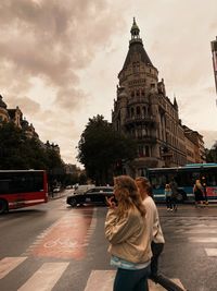 Rear view of woman on street against sky in city