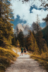 Rear view of two man walking hiking  on road