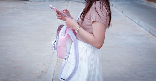 Midsection of woman using smart phone while standing on street