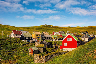 House on field by houses against sky