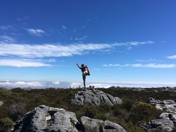 Woman stretching against blue sky