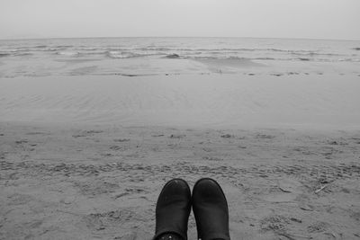 Low section of woman on beach against sky