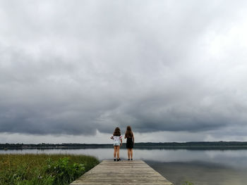 Rear view of woman walking at beach against sky