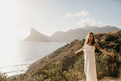 Woman standing on mountain by sea against sky