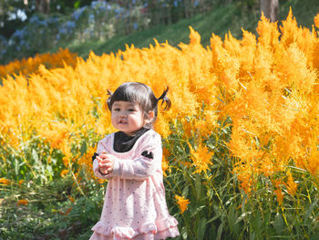 Cute baby girl standing against plants