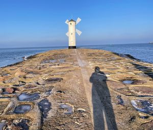 Lighthouse by sea against sky