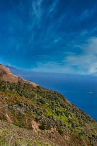 Scenic view of sea and mountains against blue sky