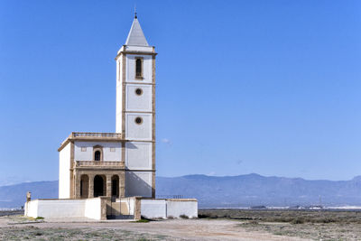 View of tower and building against clear blue sky