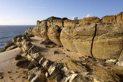 Rock formations on beach against sky