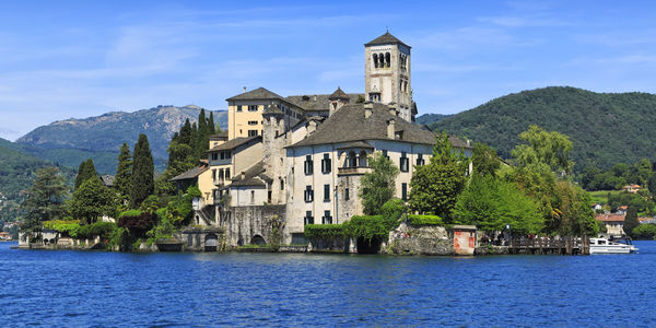 Buildings by river against sky