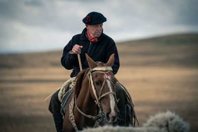 Mature man riding horse on land
