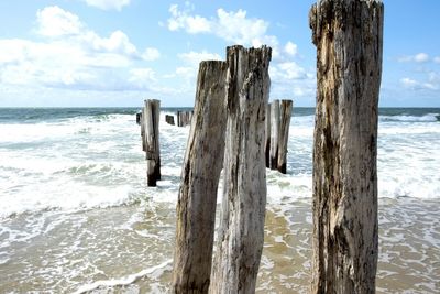 Wooden posts on beach against sky