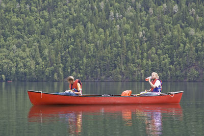 Boat sailing in lake against trees in forest