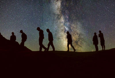 Silhouette people standing on land against sky at night