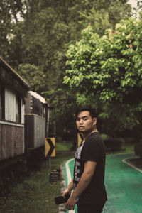 Portrait of young man standing on footpath in park