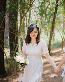 Portrait of young woman standing against trees