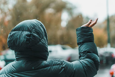 Rear view of person wearing raincoat in city during rainy season