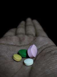 Close-up of hand holding colored pencils over black background