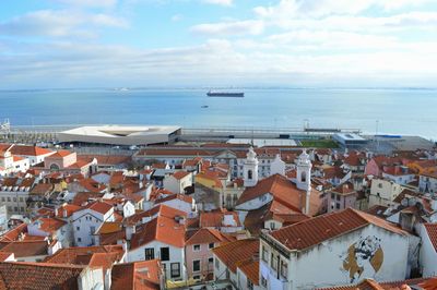 Aerial view of townscape by sea against sky