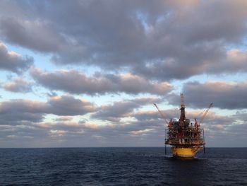 Scenic view of sea against cloudy sky at sunset