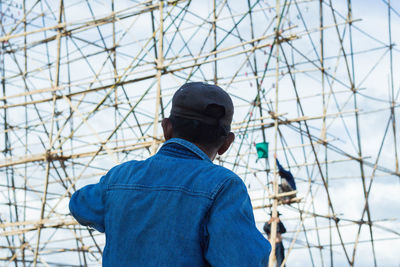 Rear view of man standing against blue sky