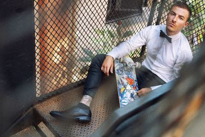 Young man sitting with skateboard on steps