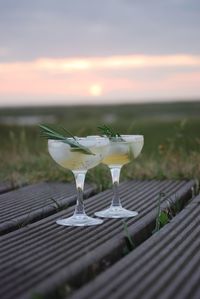 Close-up of alcoholic drinks on table against sky during sunset