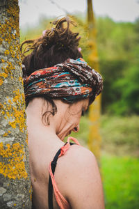 Rear view of woman wearing headscarf standing against tree at park