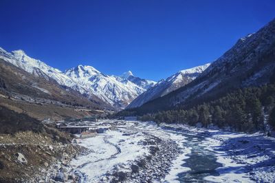 Scenic view of snowcapped mountains against clear blue sky