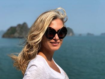 Portrait of woman wearing sunglasses against sea