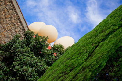 Low angle view of artificial easter eggs over wall and trees