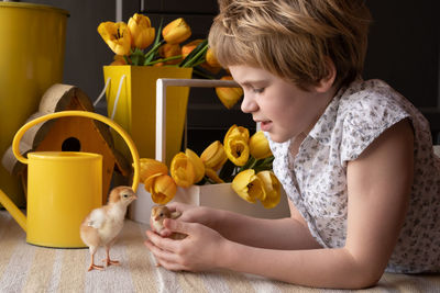 Side view of girl with chicks at home