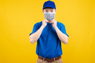 Portrait of boy standing against yellow background