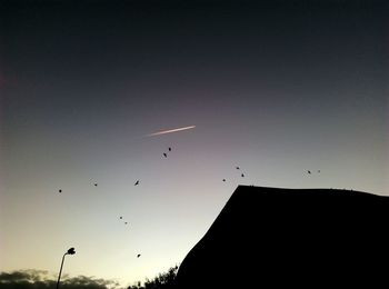 Low angle view of silhouette birds flying against sky