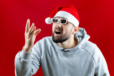 Portrait of young man wearing hat against red background