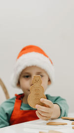 The kid is holding a gingerbread cookie in the shape of a snowman. cooking christmas cookies.