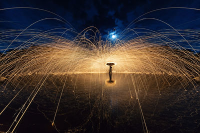 Silhouette person spinning wire wool at night