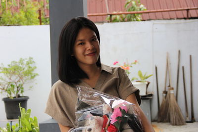 Portrait of smiling young woman by potted plants