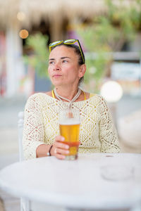 Portrait of woman drinking beer at beach cafe