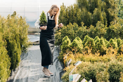 Full length of young woman standing against trees