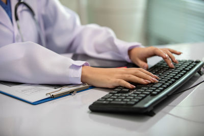 Midsection of person using laptop on table