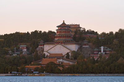 Building by lake against sky during sunset