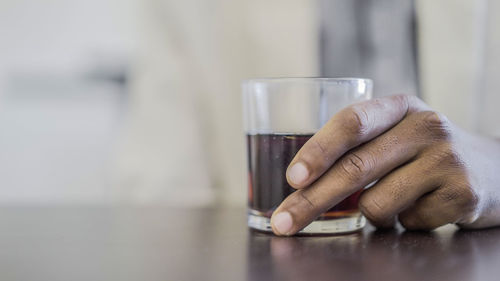 Close-up of man holding drink on table