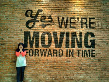 Woman standing on brick wall with text