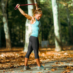 Woman stretching with elastic band outdoors in the fall, in public park