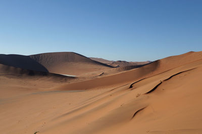 Sand dunes in desert against clear blue sky