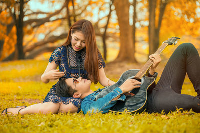 Young woman playing guitar on field