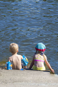 Rear view of boys sitting in water